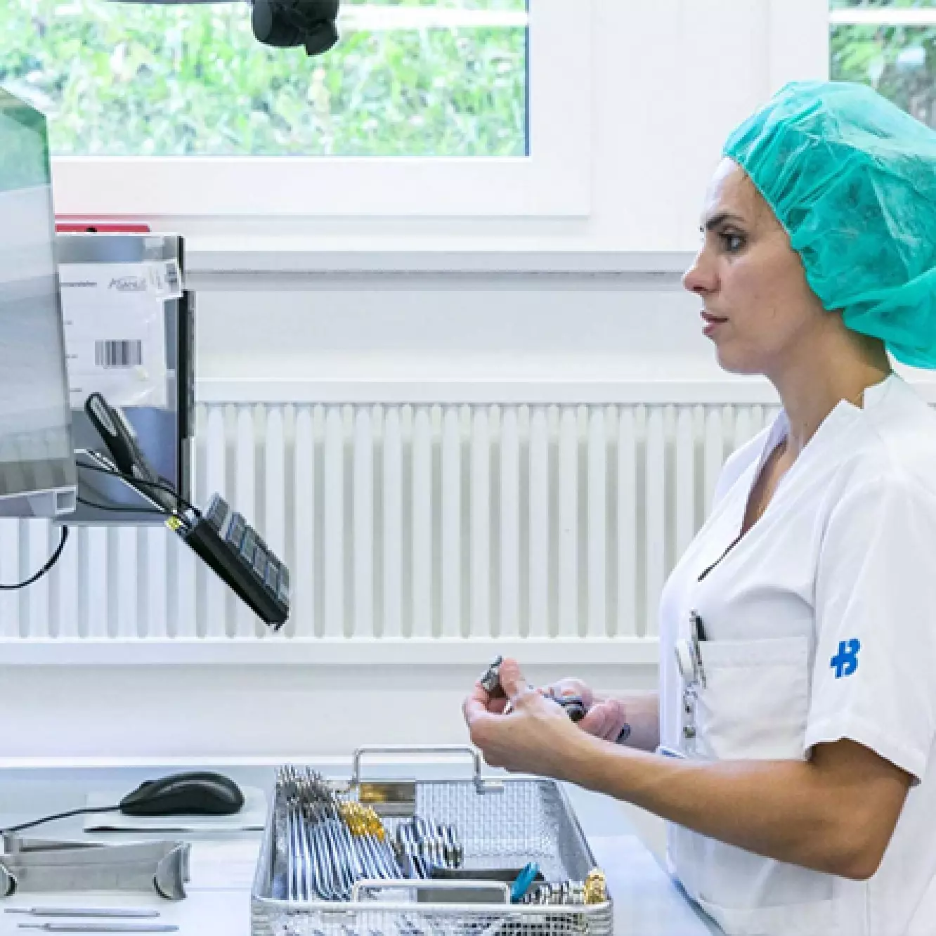 Eine Sterilisationsassistentin sortiert OP-Instrumente in Siebe ein.
