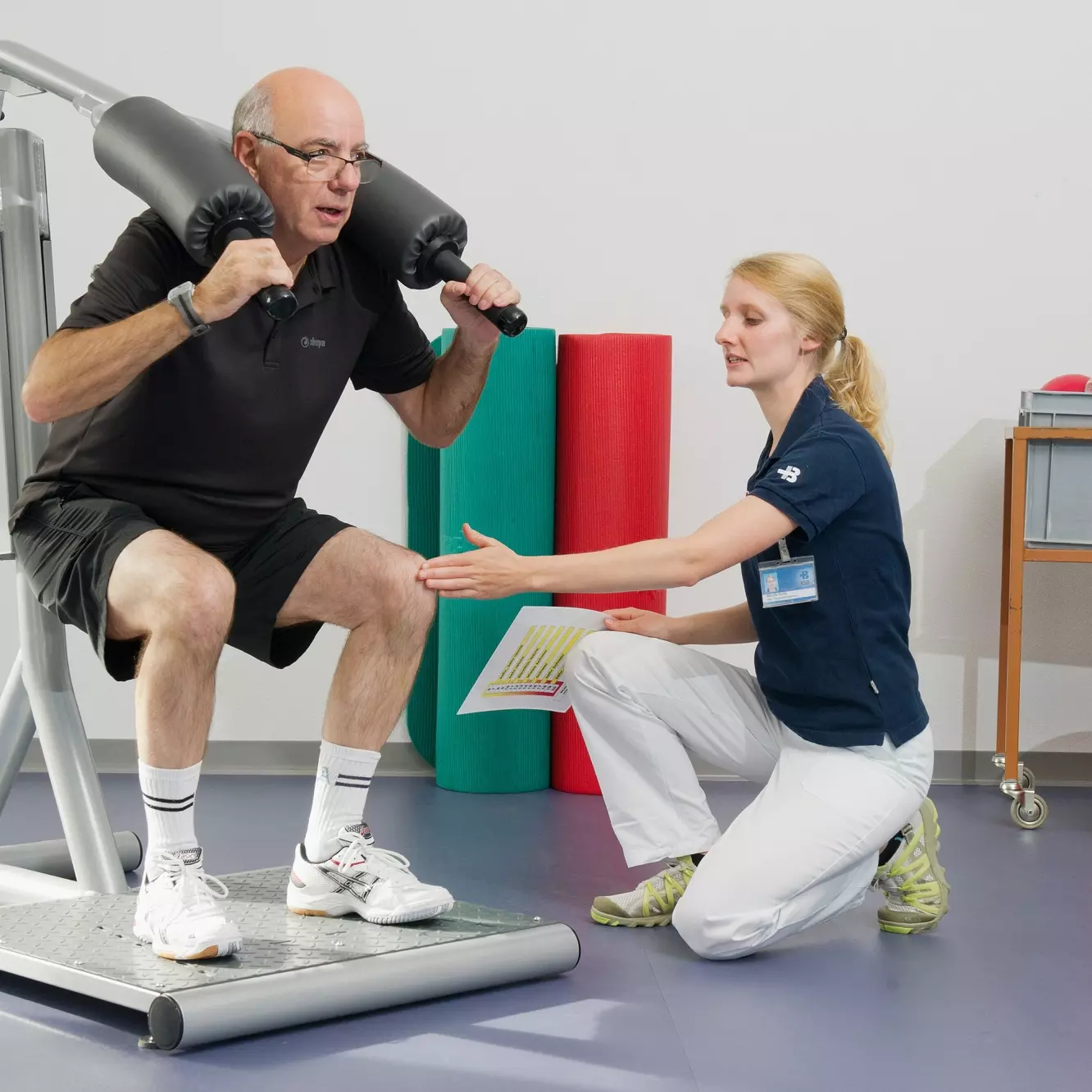 Eine Physiotherapeutin instruiert einen Patienten beim Krafttraining.