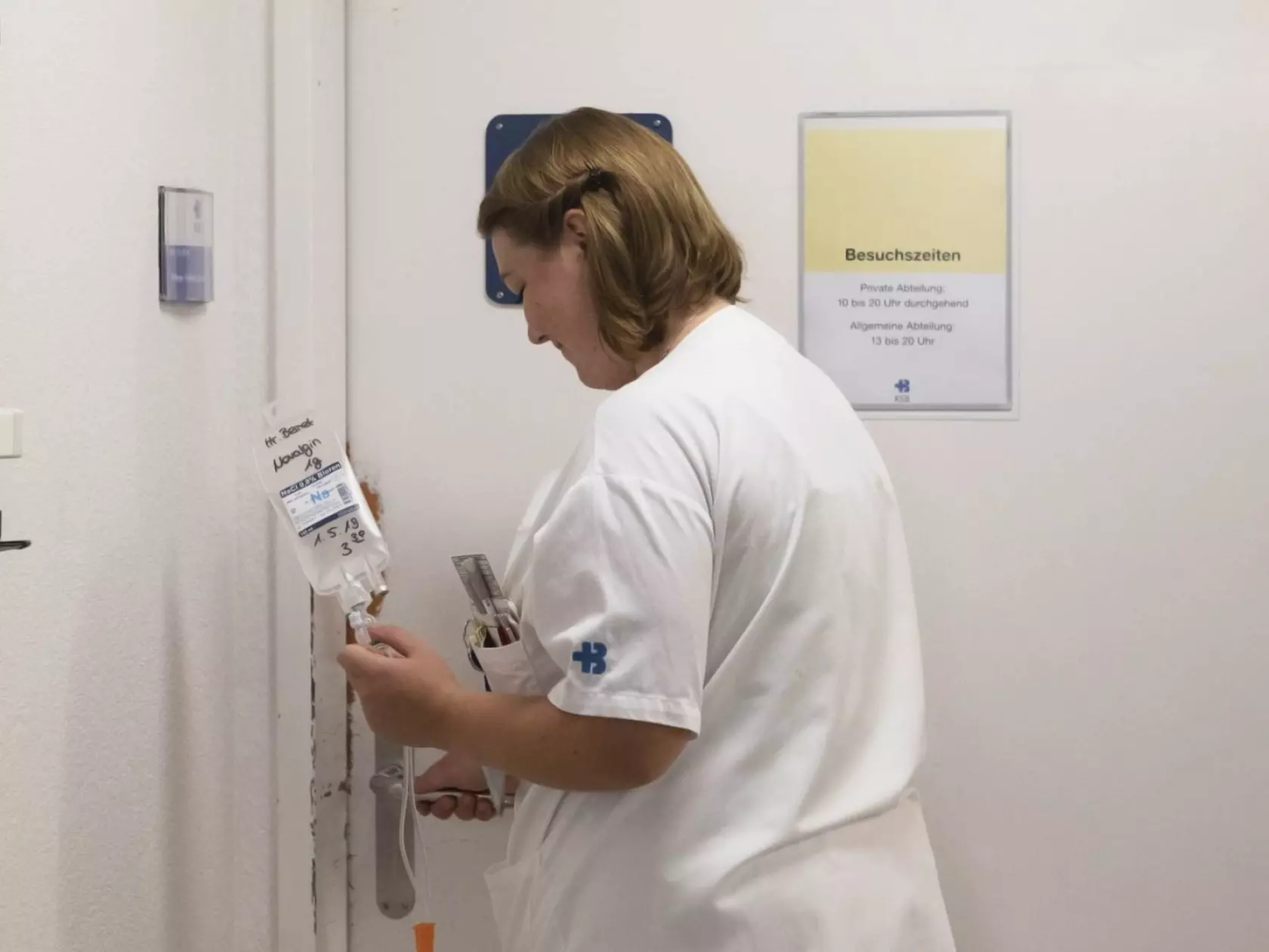 Nachtdienst: Eine Pflegefachfrau öffnet die Tür zu einem Patientenzimmer.