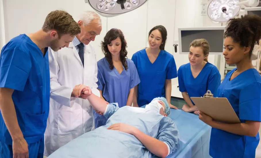 Ein erfahrener Arzt zeigt Studierenden, wie er einen Patienten behandelt.