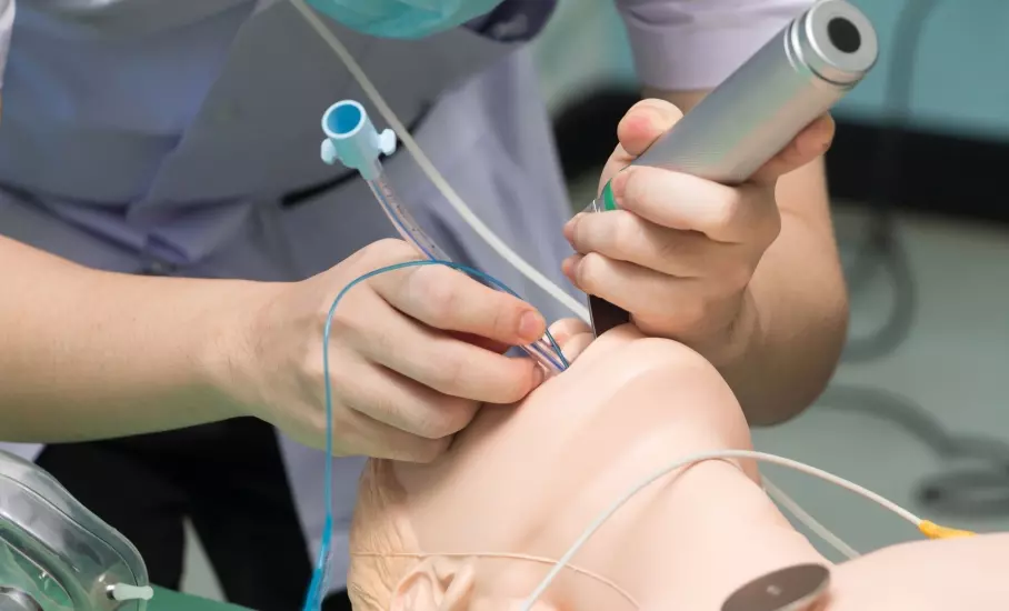 Ein Praktikant übt an einer Puppe die Intubation.